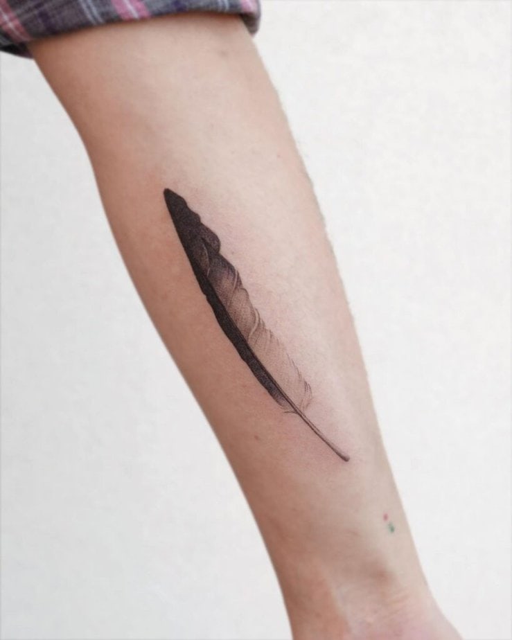 A long feather tattoo on the forearm