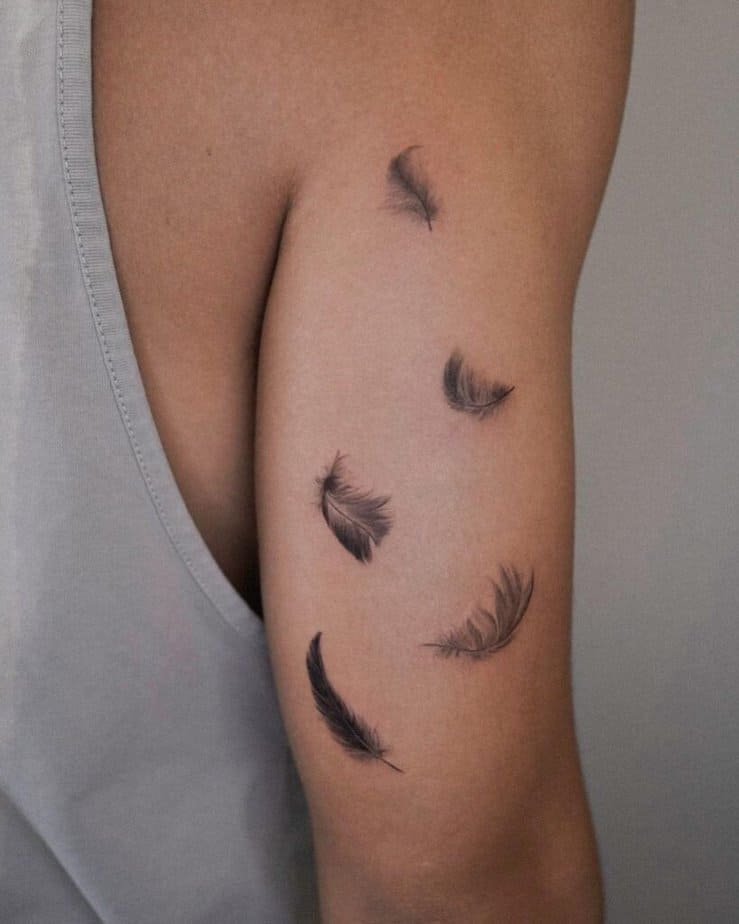 A tattoo of a couple of feathers on the back of the arm