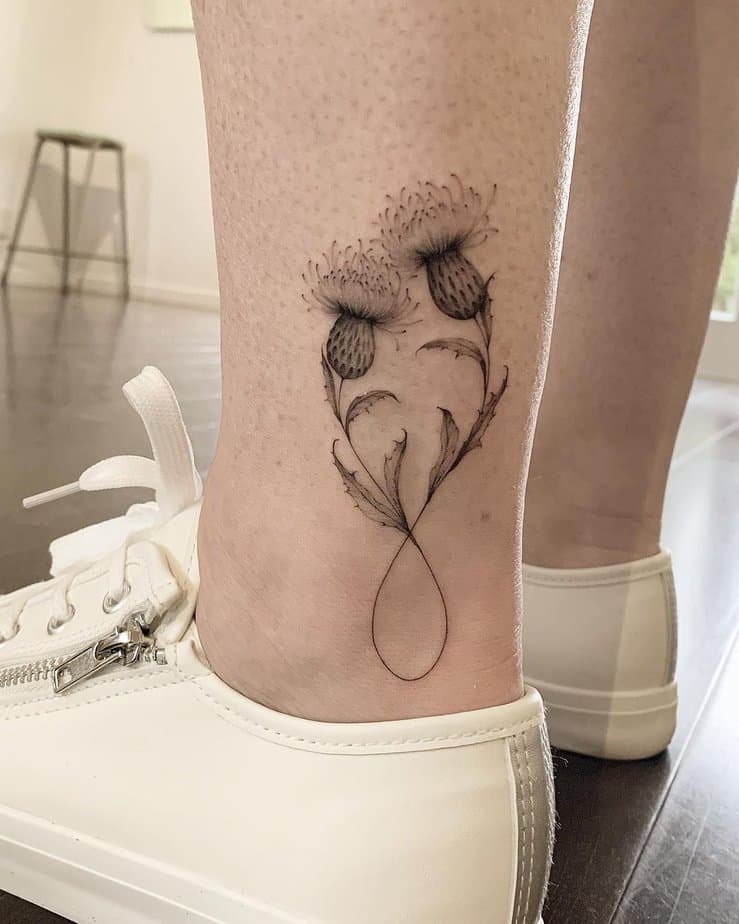 A tattoo of two infinity thistles above the ankle