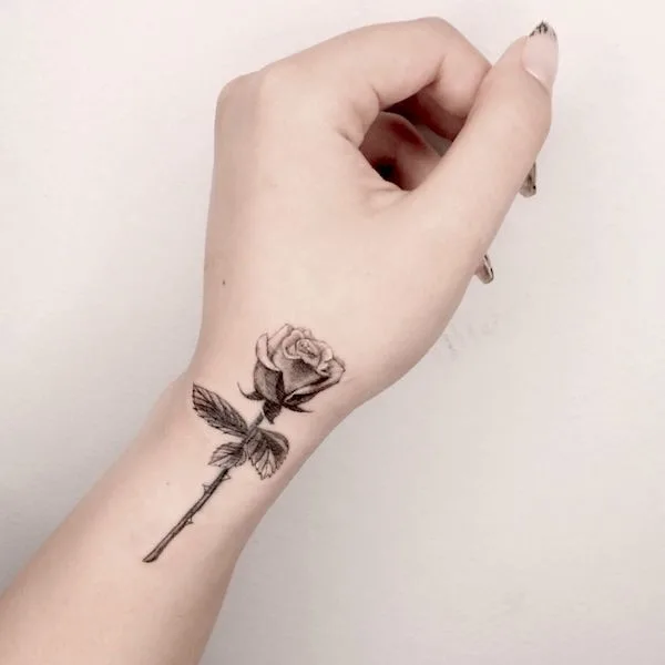 Black and grey rose tattoo on the side wrist