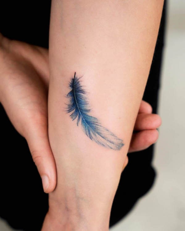 Small blue feather wrist tattoo