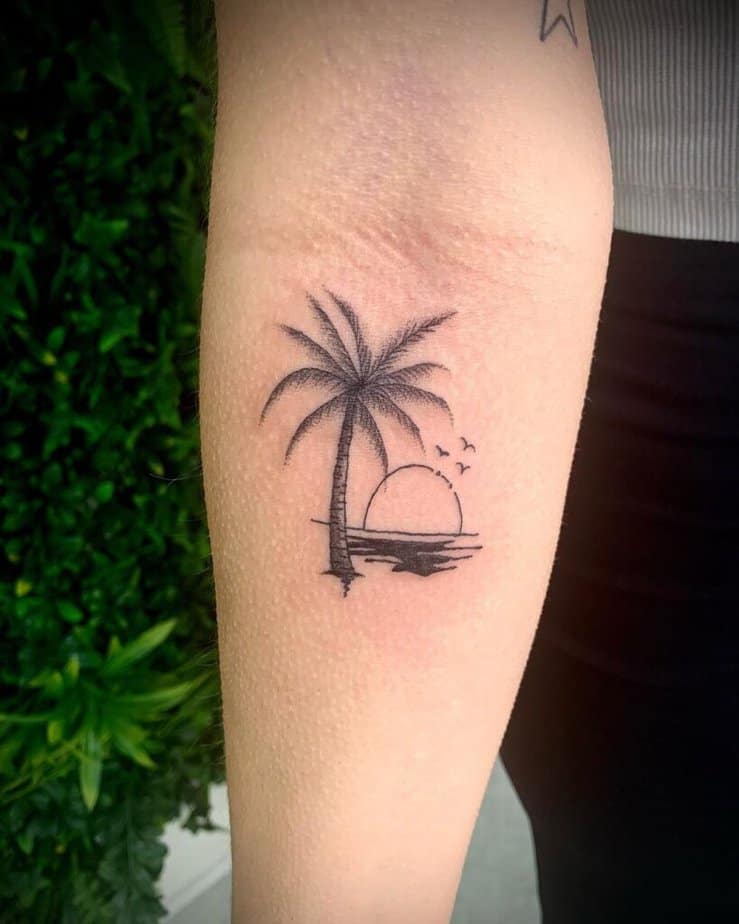 A palm tree scene tattoo on the forearm